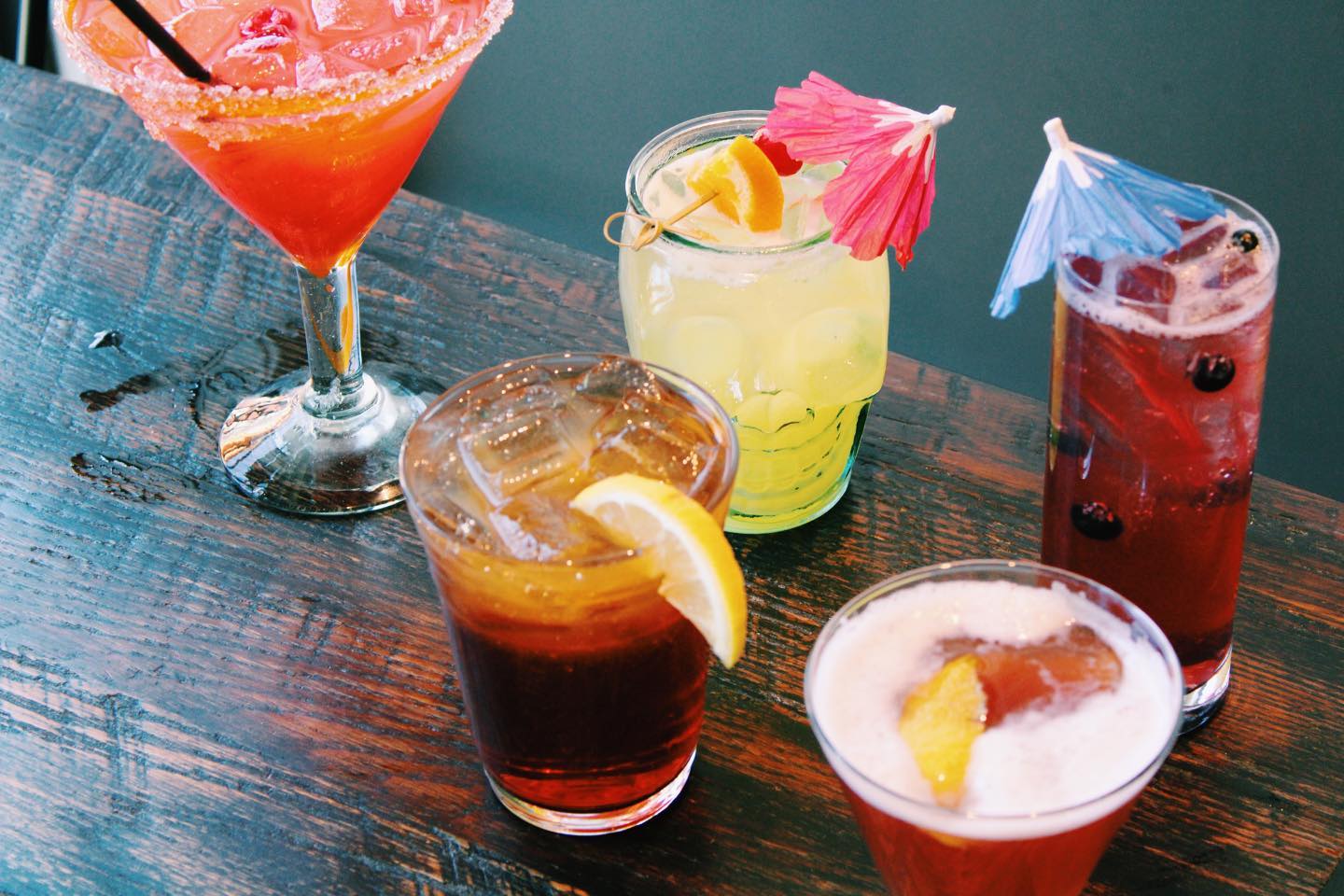 An image of 5 cocktails on a wooden table.