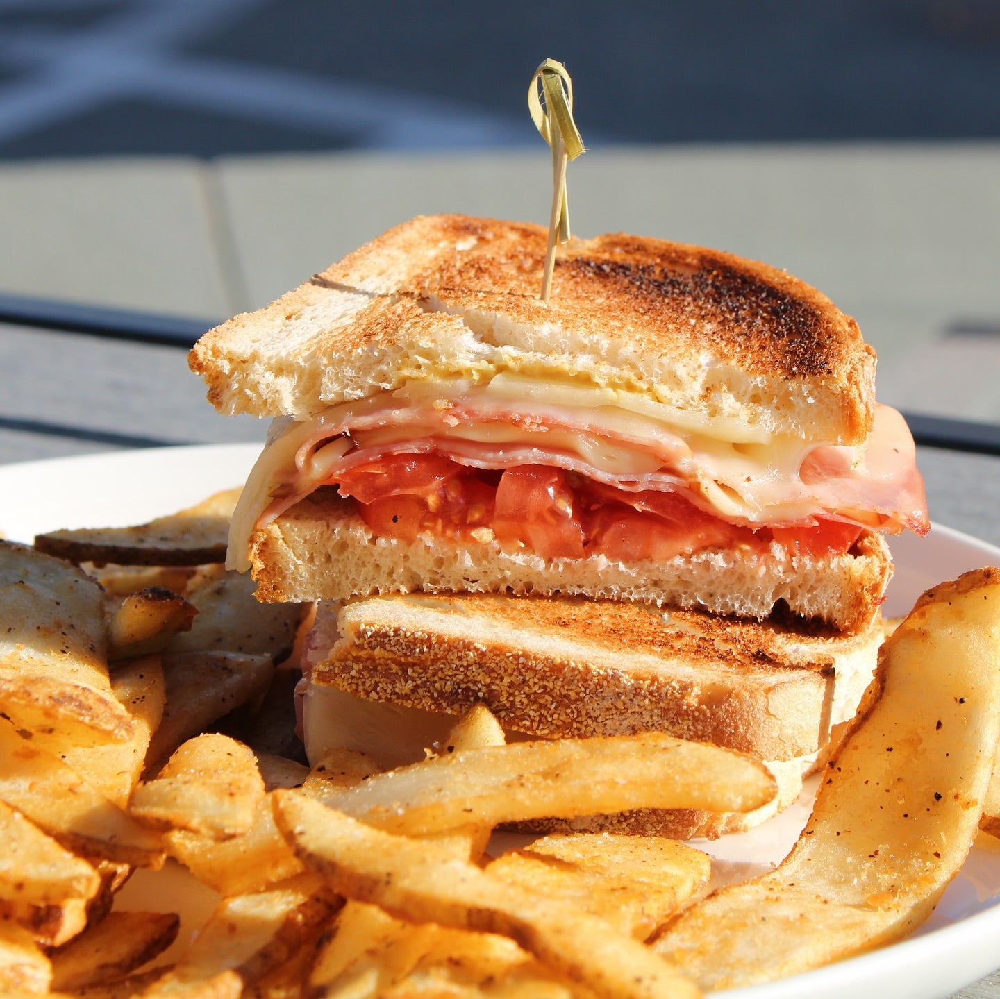 An image of a Bacon, Lettuce, Tomato (BLT) melt on a white plate served with french fries.
